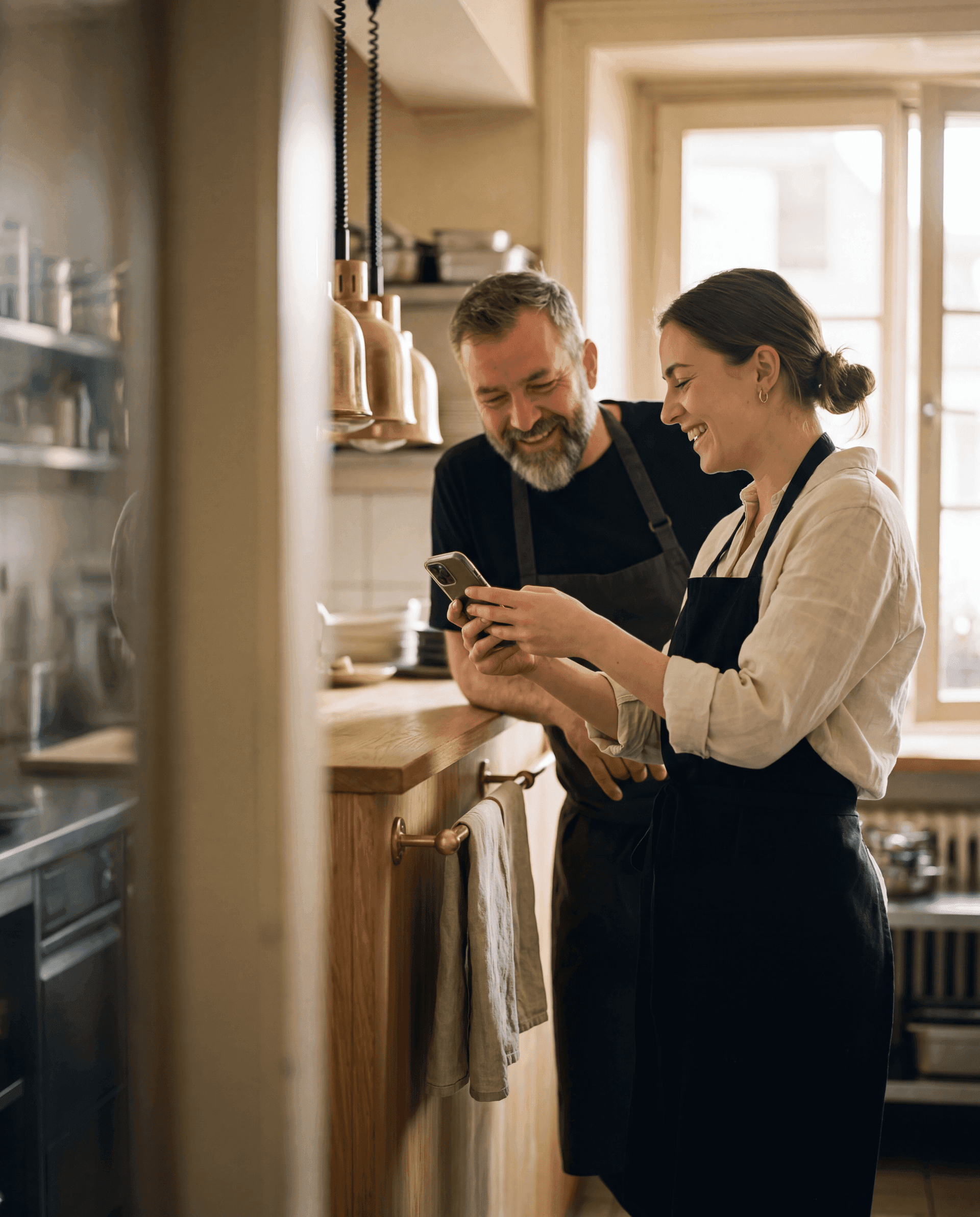 Two Swiss restaurant staff sharing a moment over a phone.